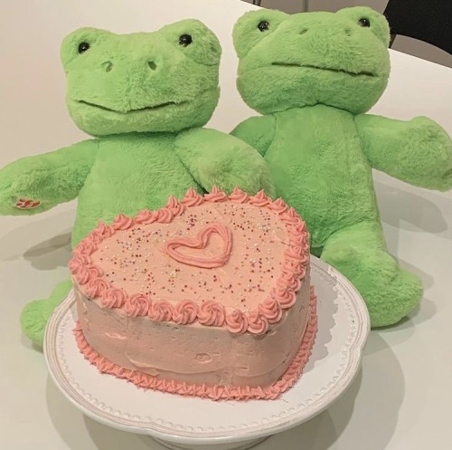 two frogs with a pink cake